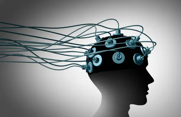 Brain linking and connecting the human mind with computers and the internet as a group of wired electrodes attached to a patients head as a neurology and neuroscience symbol as a 3D illustration.