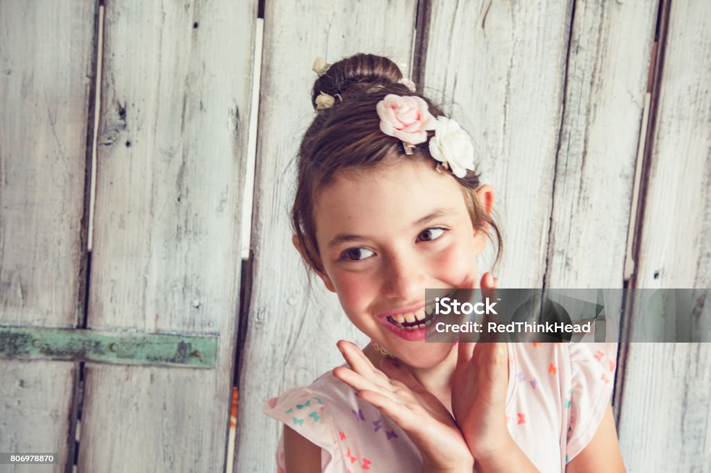 Delighted little girl posing Cheerful little girl with flowers in her hair posing in front of white background Child Stock Photo