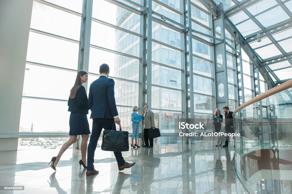 Business people walking in glass building Business people walking in modern glass office building Business Stock Photo