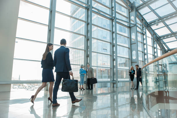 Business people walking in glass building Business people walking in modern glass office building office building interior stock pictures, royalty-free photos & images