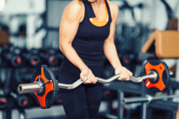 istock Woman exercising in gym with barbell weights 806998788