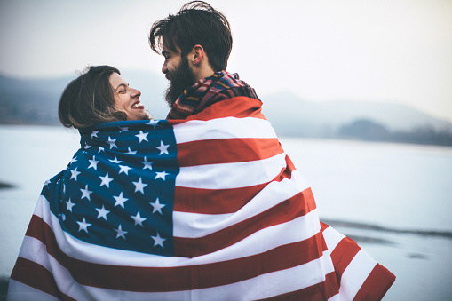 Couple on cold winter day in nature, having fun, wrapped in American flag