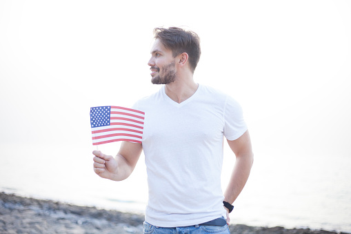 4 Th of July,Young man holding American flag at the beach