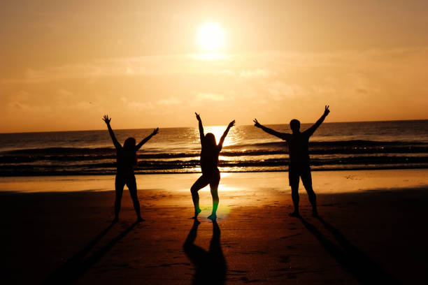 istock Friends with arms outstretched on beach during sunrise 807096204