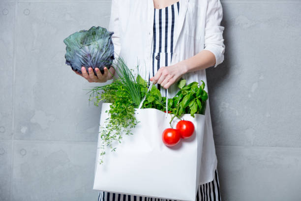 istock woman holding bag with organic herbs and vegetables 807110902