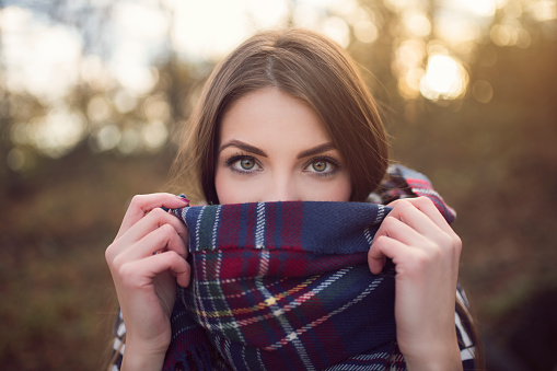 Portrait of a beautiful young woman with face wrapped into a plaid scarf.