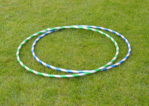 Closeup of mass produced plastic hula hoops on a lawn in the summer.