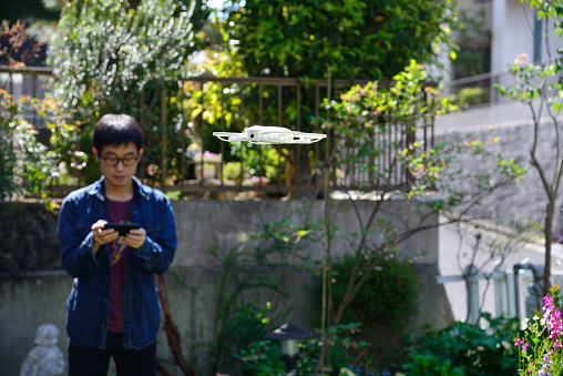 A man standing in his garden, playing with a drone.