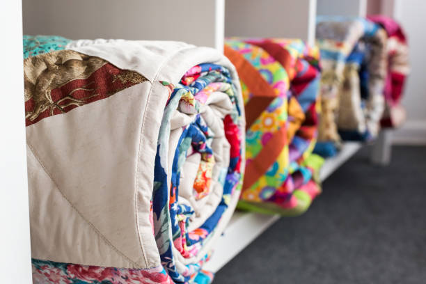 patchwork, sewing and fashion concept - bright finished quilts in the studio at white shelves with three storage compartments, the warehouse of finished products, side view, selective focus stock photo