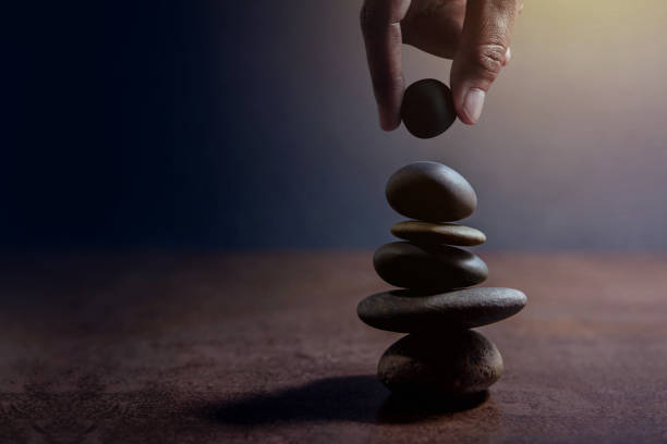 istock Balance concept between of Life and work present by Hand setting a natural zen rock stone on Stack, Side view and Dark light 807187920