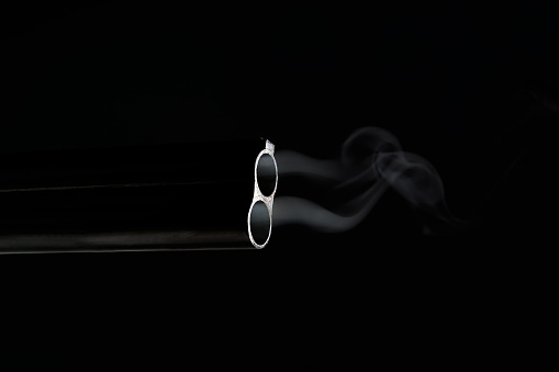 Smoke from a barrel from a gun on a black background