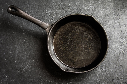 Cast iron pan on rustic black stone background close up -  empty black frying pan frying skillet with copy space