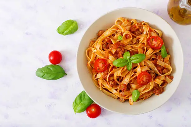 Pasta Fettuccine Bolognese with tomato sauce in white bowl. Flat lay. Top view