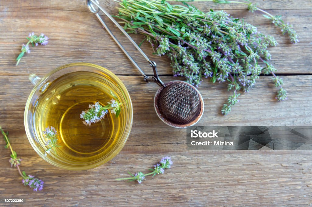 herbal tea Healthy herbal tea with bunch of fresh wild thyme and vintage tea-strainer on old wooden background. Cup of thyme tea, herbal drink. Thyme Stock Photo