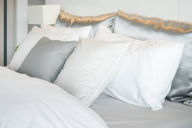 istock Gray color scheme pillows setting on bed with satin finished style bedding 807235890