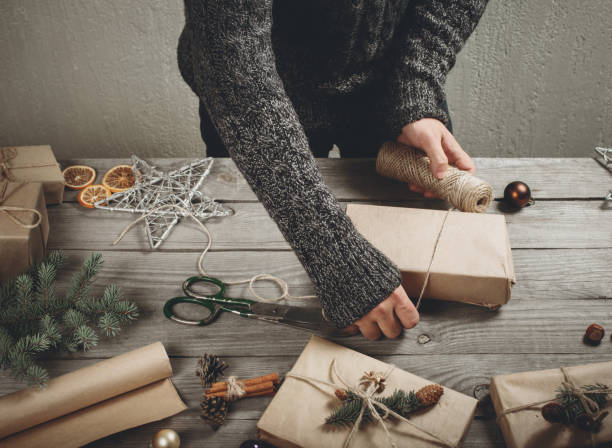 istock Male hands wrap christmas present on wooden table 807239714