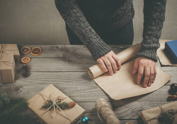 istock Male hands wrapping xmas present on wooden table close up 807239736