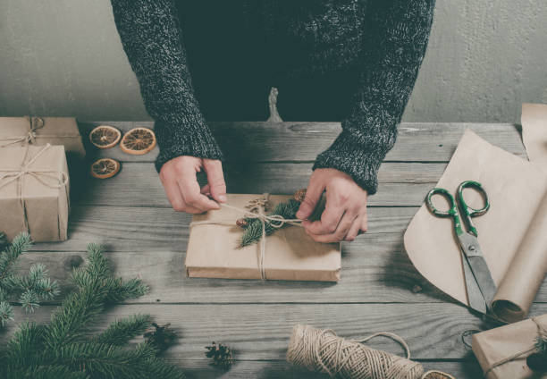 istock Male hands wrapping Christmas gift on wooden table 807241788