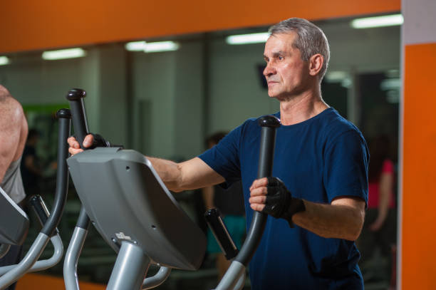 istock Senior man exercising on elliptical machine in gym 807242914