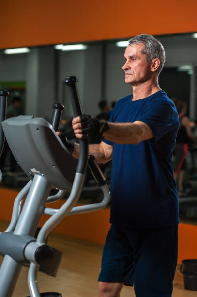 istock Senior man exercising on elliptical machine in gym 807244496
