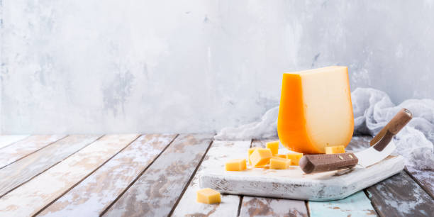 Delicious Gouda cheese Delicious dutch gouda cheese with cheese cubes and special knife on old wooden table. Copy space. gouda cheese stock pictures, royalty-free photos & images