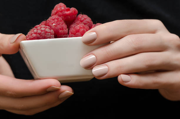 istock Female hands with beige manicure holding bowl with raspberry. 807259282