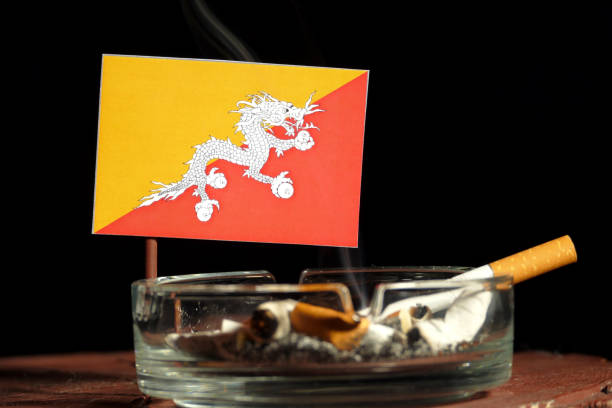 Bhutan flag with burning cigarette in ashtray isolated on black background stock photo