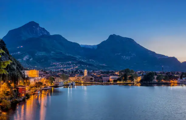 Beautiful landscape and cityscape at Riva del Garda with fog over the mountains of Arco iduring sunrise at a early summer morning.