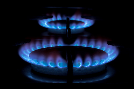 Gas burner on the stove. Gas fire on black background. Focus on the near burner