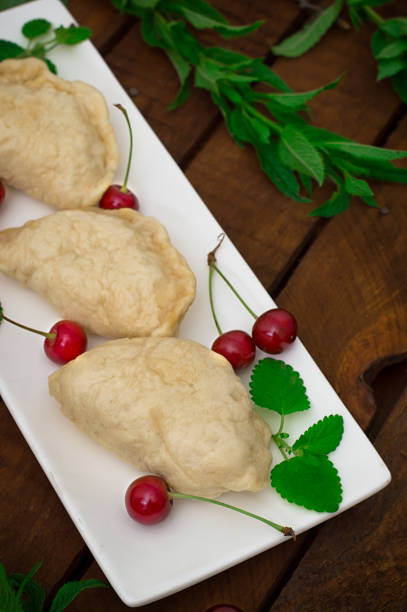 istock Homemade dumplings with cherries. Wooden rustic background. Close-up. Top view 807277586