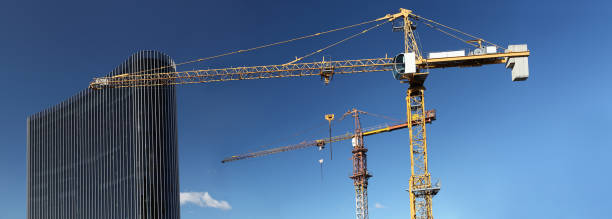 en vertu du chantier de construction avec grue et verre gratte-ciel dans le ciel bleu, le concept de succès commercial - steel construction site construction glass photos et images de collection