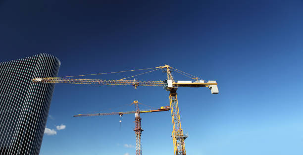 en vertu du chantier de construction avec grue et verre gratte-ciel dans le ciel bleu, le concept de succès commercial - steel construction site construction glass photos et images de collection