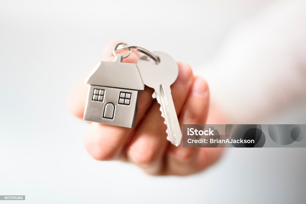 Real estate agent giving house keys Holding house keys on house shaped keychain concept for buying a new home Key Stock Photo