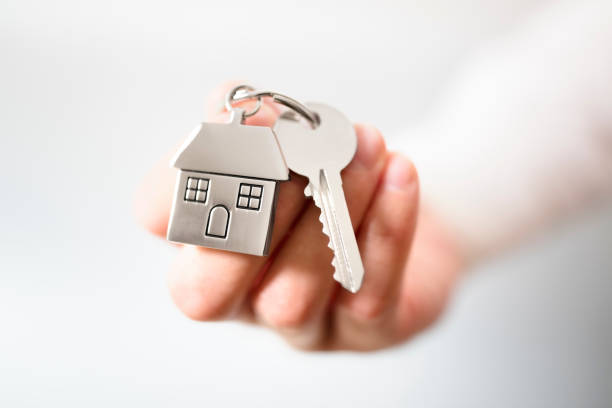 Real estate agent giving house keys Holding house keys on house shaped keychain concept for buying a new home house key photos stock pictures, royalty-free photos & images