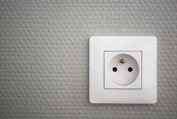 Photo of White french electrical outlet/plug on a wall.