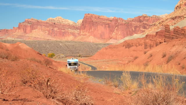 RV Camper traveling past mesa and butte mountain formations in red rock desert
