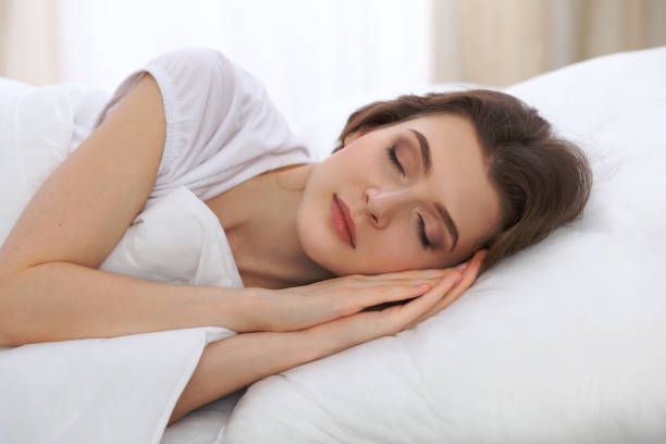 istock Beautiful young woman sleeping while lying in her bed and relaxing comfortably. It is easy to wake up for work or the day off. Concept of pleasant and rest reinstatement for active life 807319562
