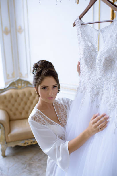 istock Beautiful bride in robe is watching a wedding dress 807332784