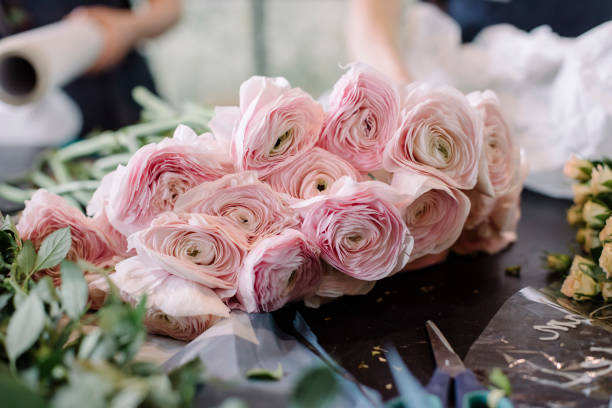 istock Florist workplace: tender fresh Ranunculus and little roses on the old wooden table with other greenery 807340264