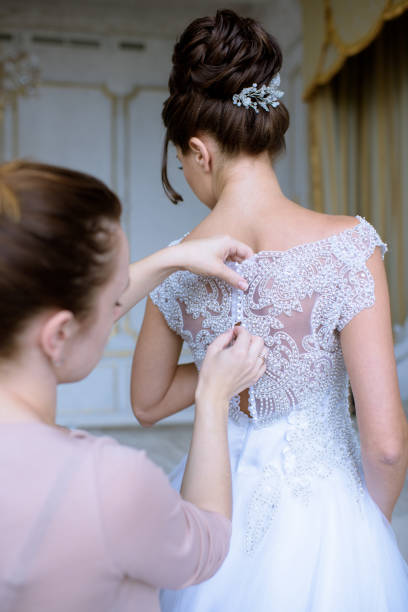 istock Bridesmaid is lacing white wedding dress for beautiful bride 807340340