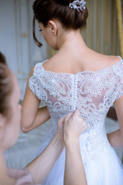 istock Bridesmaid is lacing white wedding dress for beautiful bride 807340438