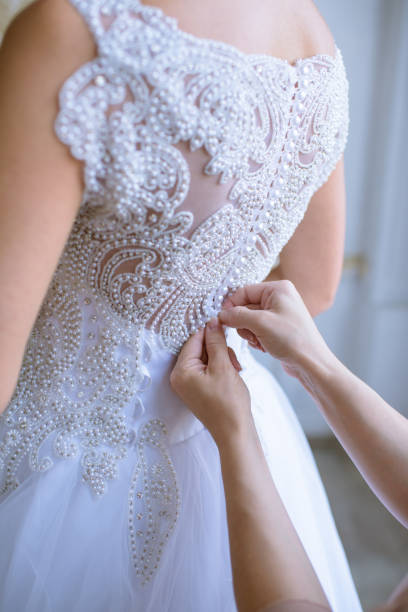 istock Bridesmaid is lacing white wedding dress for beautiful bride 807340642