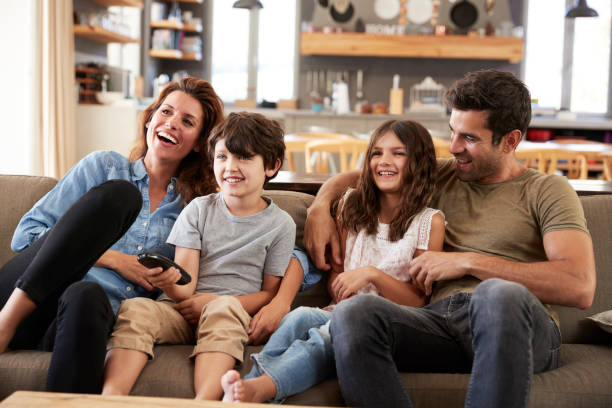 istock Family Sitting On Sofa In Open Plan Lounge Watching Television 807355758