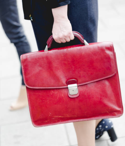Mid age adult business woman holds red leather briefcase stock photo
