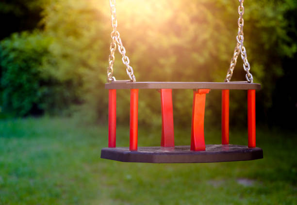 Old vintage wooden red teeter in sunset light. Horizontal crop, close up and focus on swing