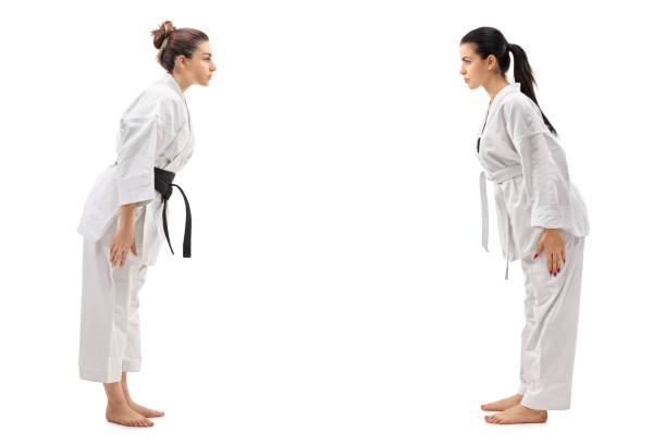 dos mujeres jóvenes vestidas con kimonos cediendo uno al otro - martial arts women tae kwon do black belt fotografías e imágenes de stock