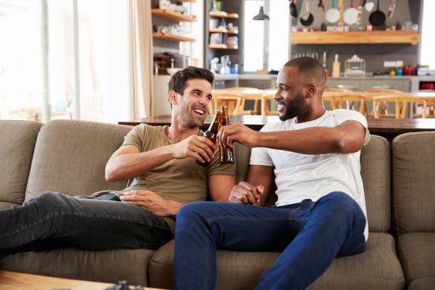 two male friends sit on sofa and watch sports on television - fan sport football male imagens e fotografias de stock