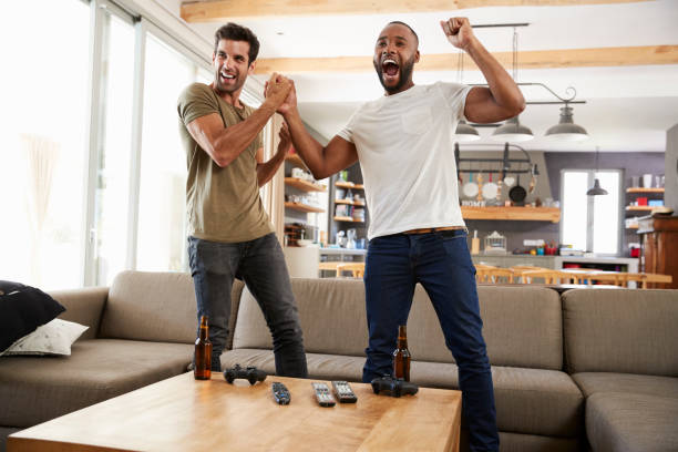 two excited male friends celebrate watching sports on television - fan sport football male imagens e fotografias de stock