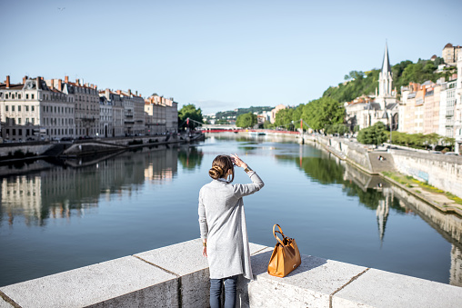 Beautiful and elegant woman enjoying morning city standing near the river in Lyon old town in France