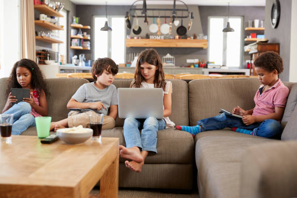 istock Group Of Children Sitting On Sofa Using Digital Devices 807395430